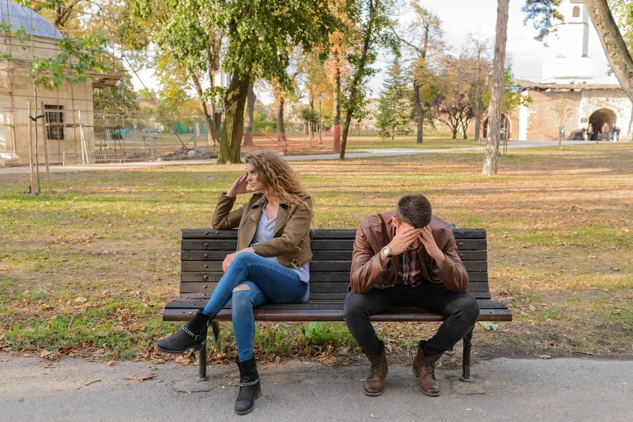 man and woman sitting on a bench unhappily