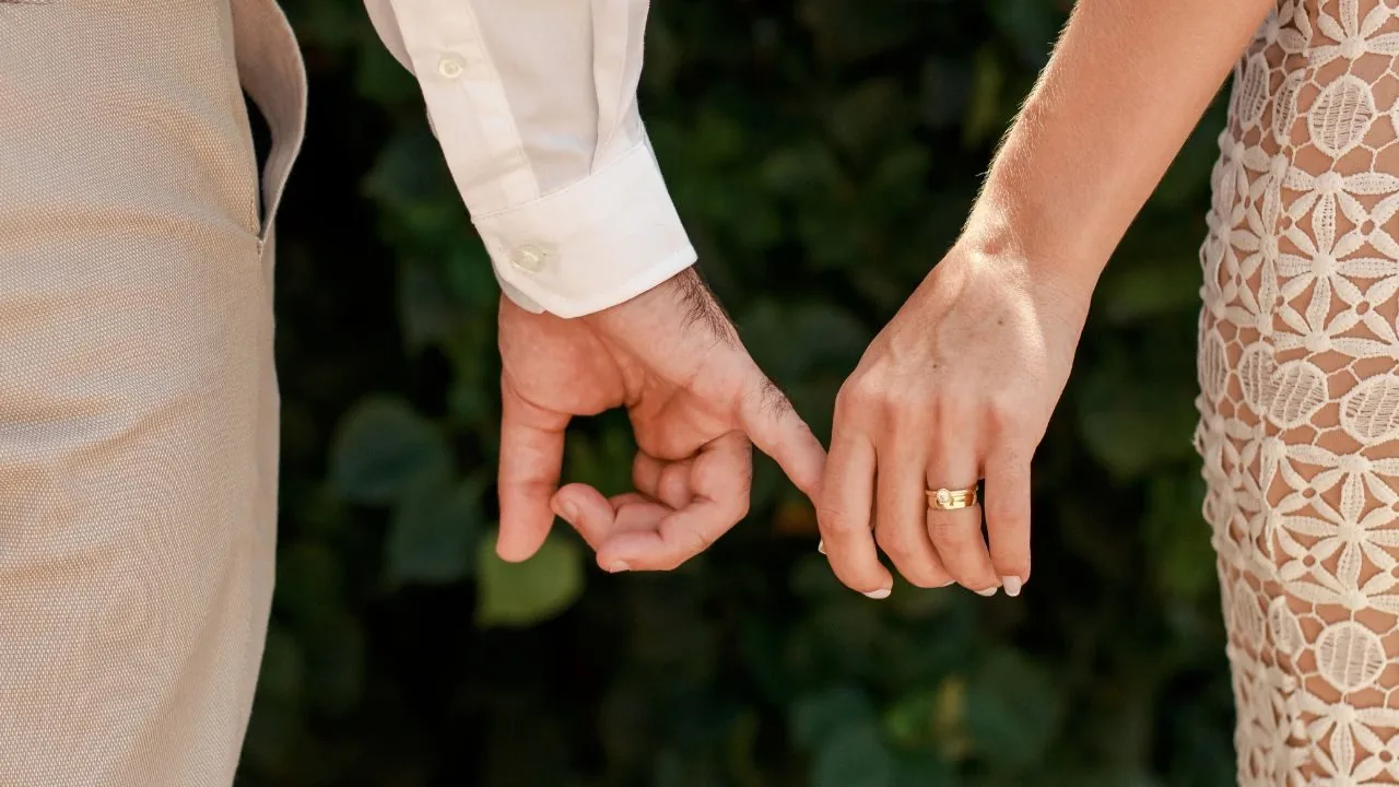 Close up image of a husband and wife holding hands