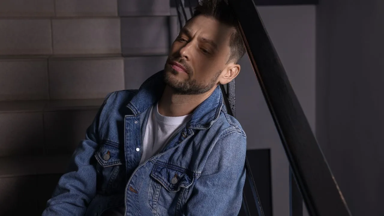Unhappy man sitting on the stair case with his head against the stairs rail