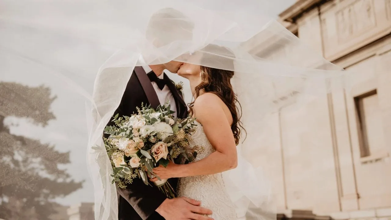 Bride and groom kissing under veil